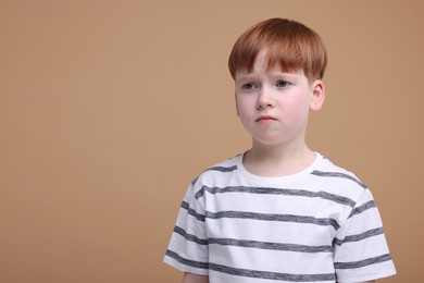 Photo of Portrait of sad little boy on beige background, space for text