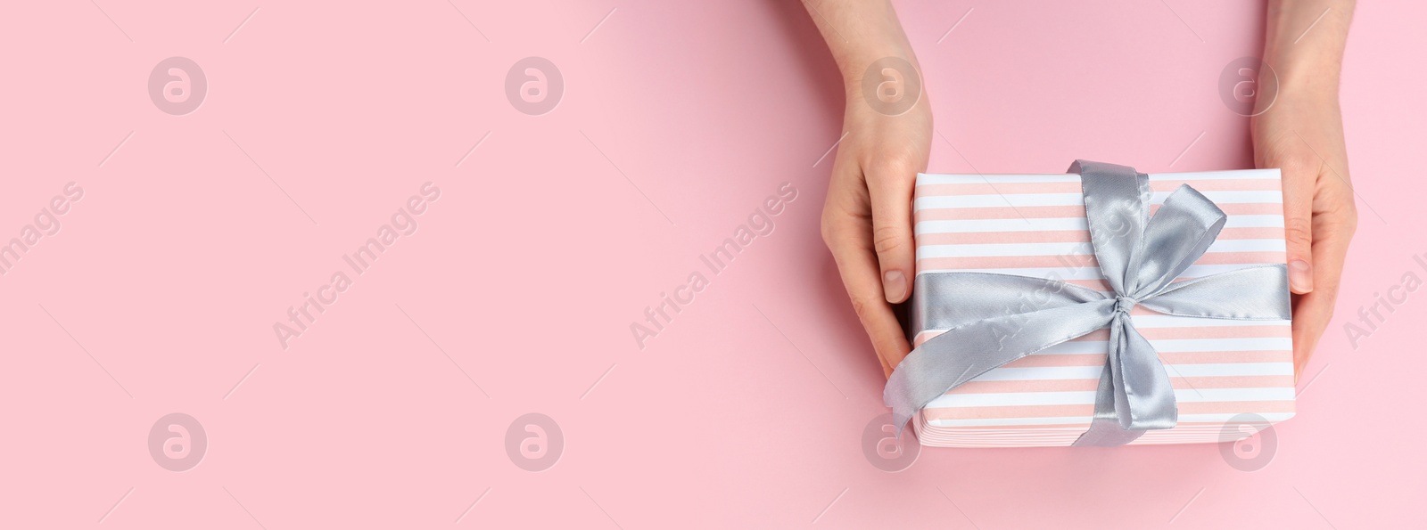 Image of Woman with gift box and space for text on pink background, top view. Banner design