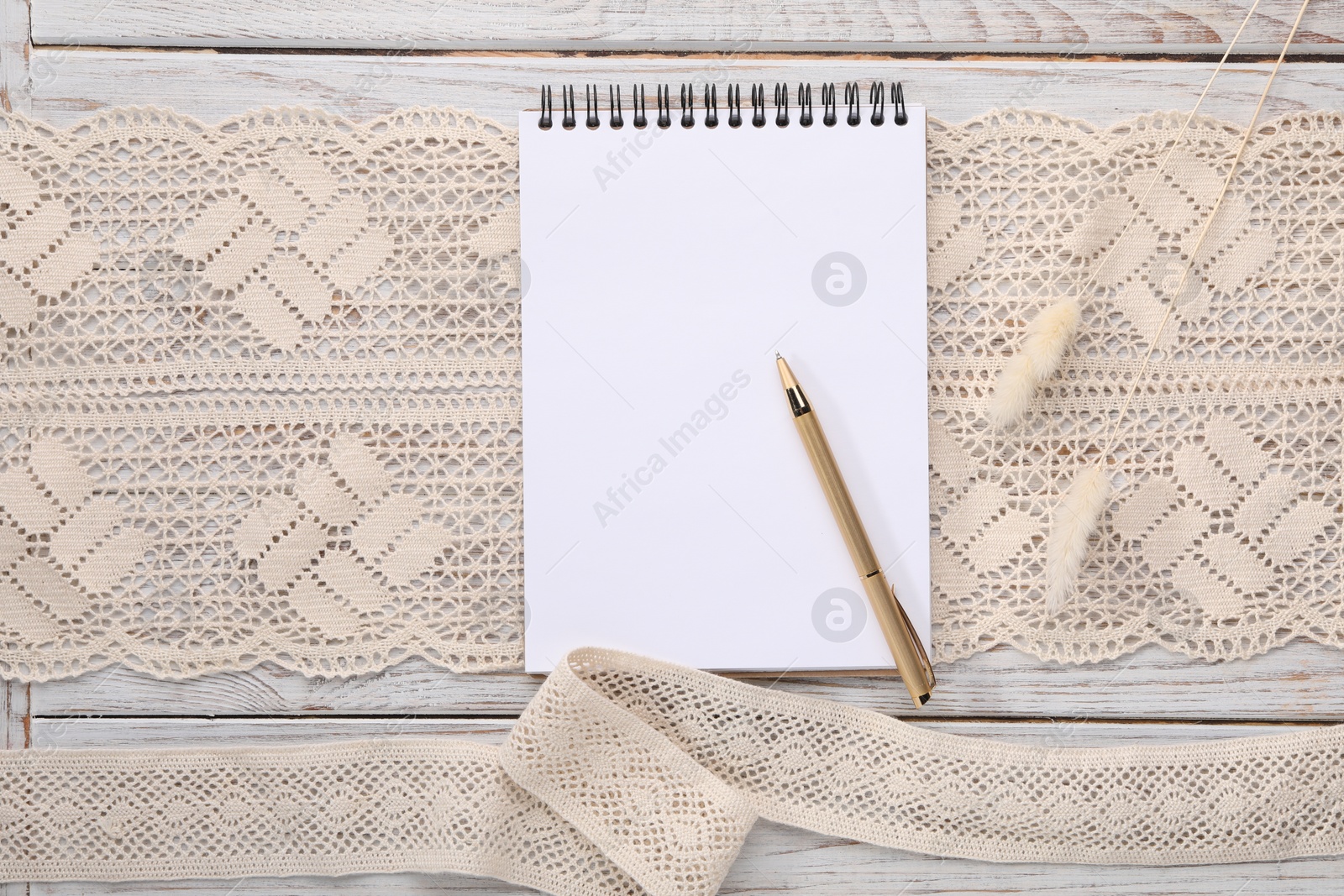 Photo of Guest list. Notebook, pen, spikelets and lace ribbons on wooden background, flat lay