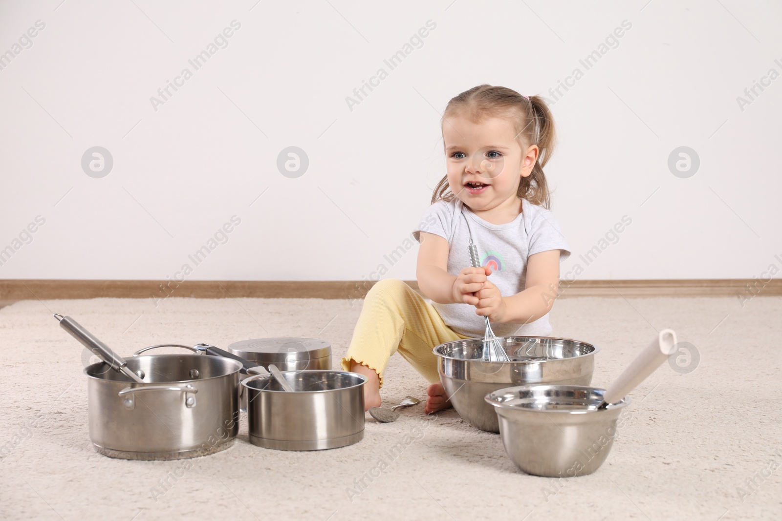 Photo of Cute little girl with cookware at home