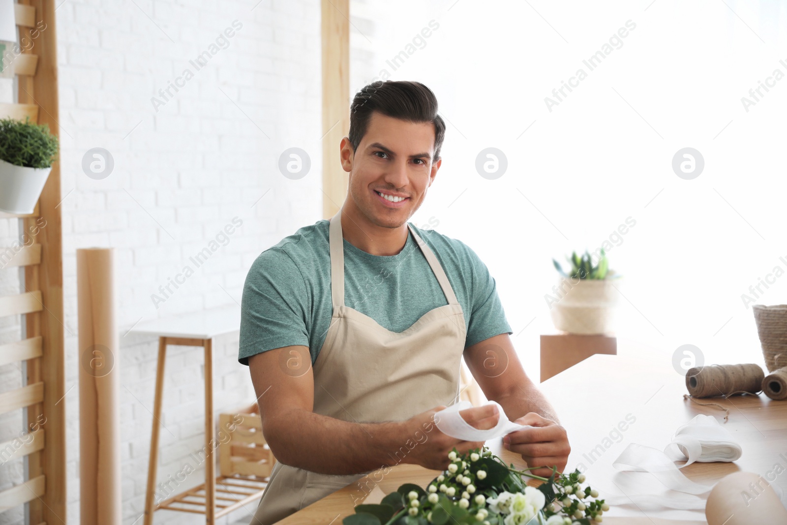 Photo of Florist making beautiful bouquet at table in workshop