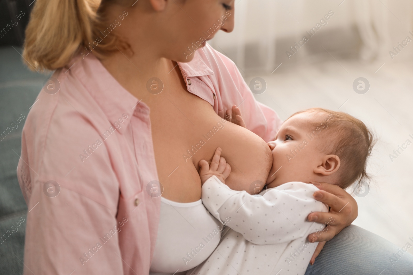 Photo of Young woman breastfeeding her baby at home