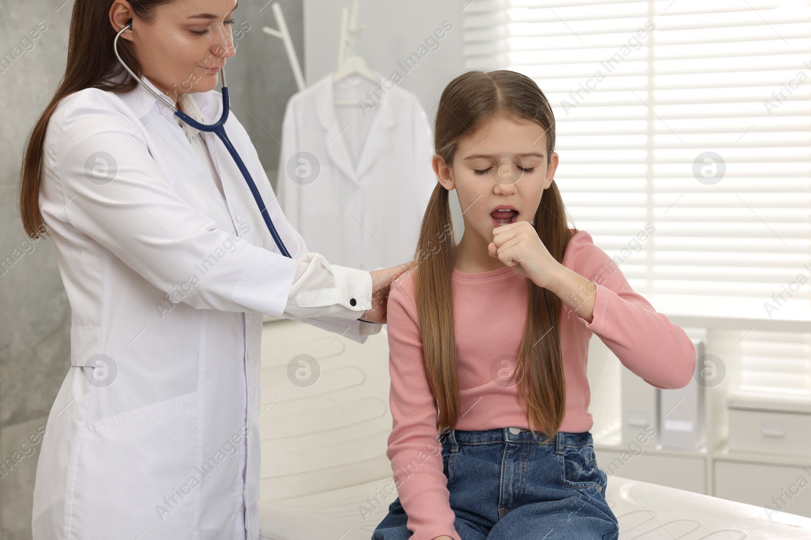 Photo of Doctor examining coughing girl in hospital. Cold symptoms