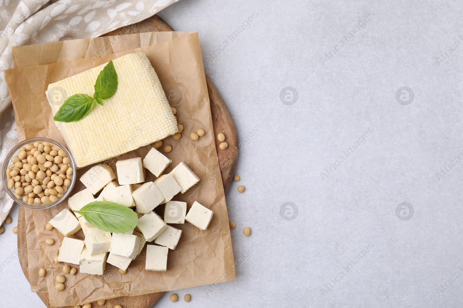 Photo of Delicious tofu cheese, basil and soybeans on light gray table, flat lay. Space for text