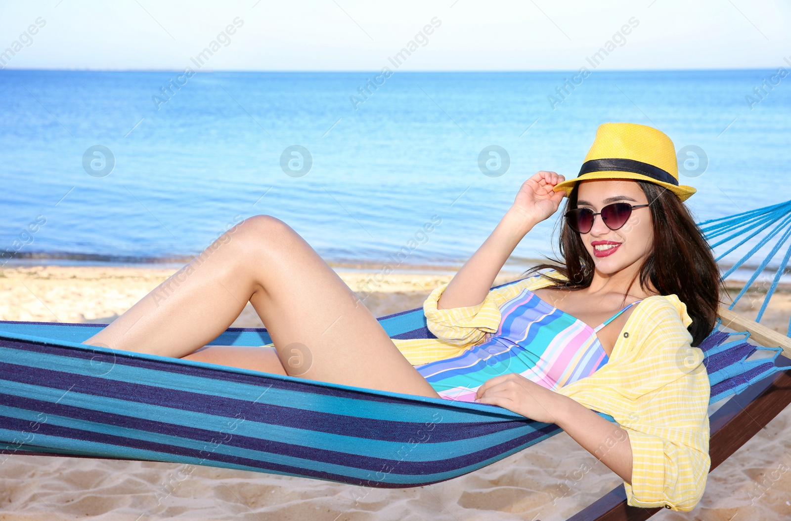 Photo of Young woman relaxing in comfortable hammock at seaside