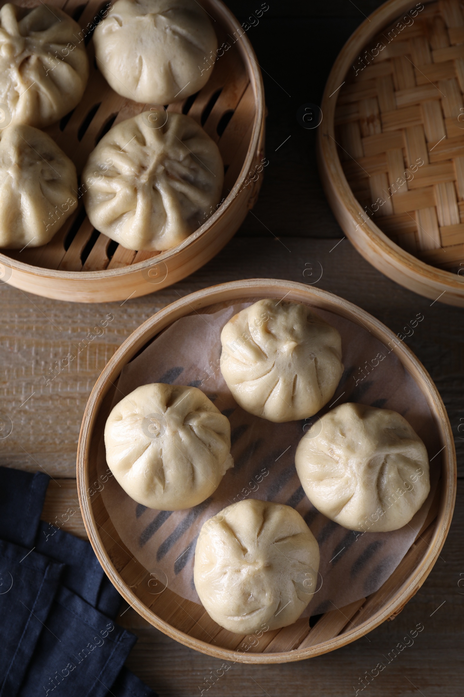 Photo of Delicious bao buns (baozi) on wooden table, flat lay