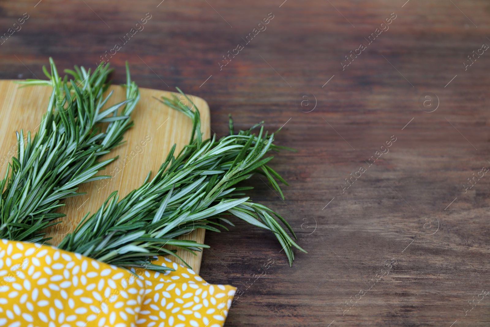 Photo of Bunches of fresh rosemary on wooden table, closeup with space for text. Aromatic herb