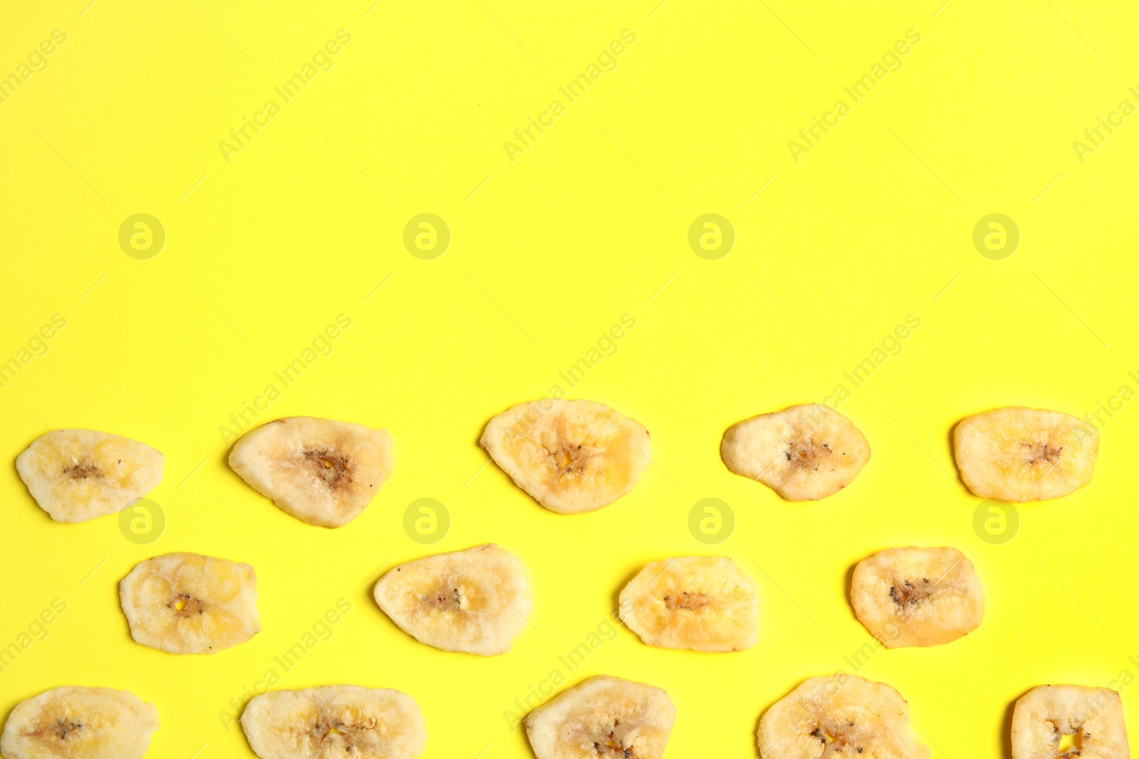 Photo of Flat lay composition with banana slices on color background, space for text. Dried fruit as healthy snack