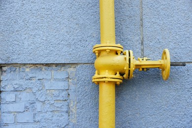 Photo of Yellow gas pipe on grey wall outdoors, space for text