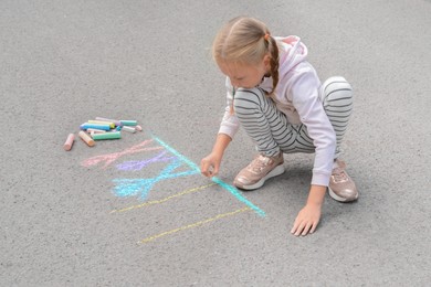 Little child drawing happy family with chalk on asphalt