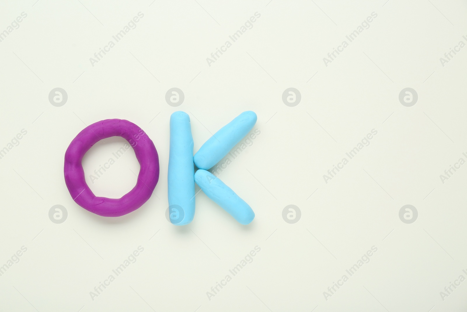 Photo of Word Ok made of colorful plasticine on white background, top view. Space for text