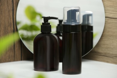 Photo of Different face cleansing products near mirror on white table