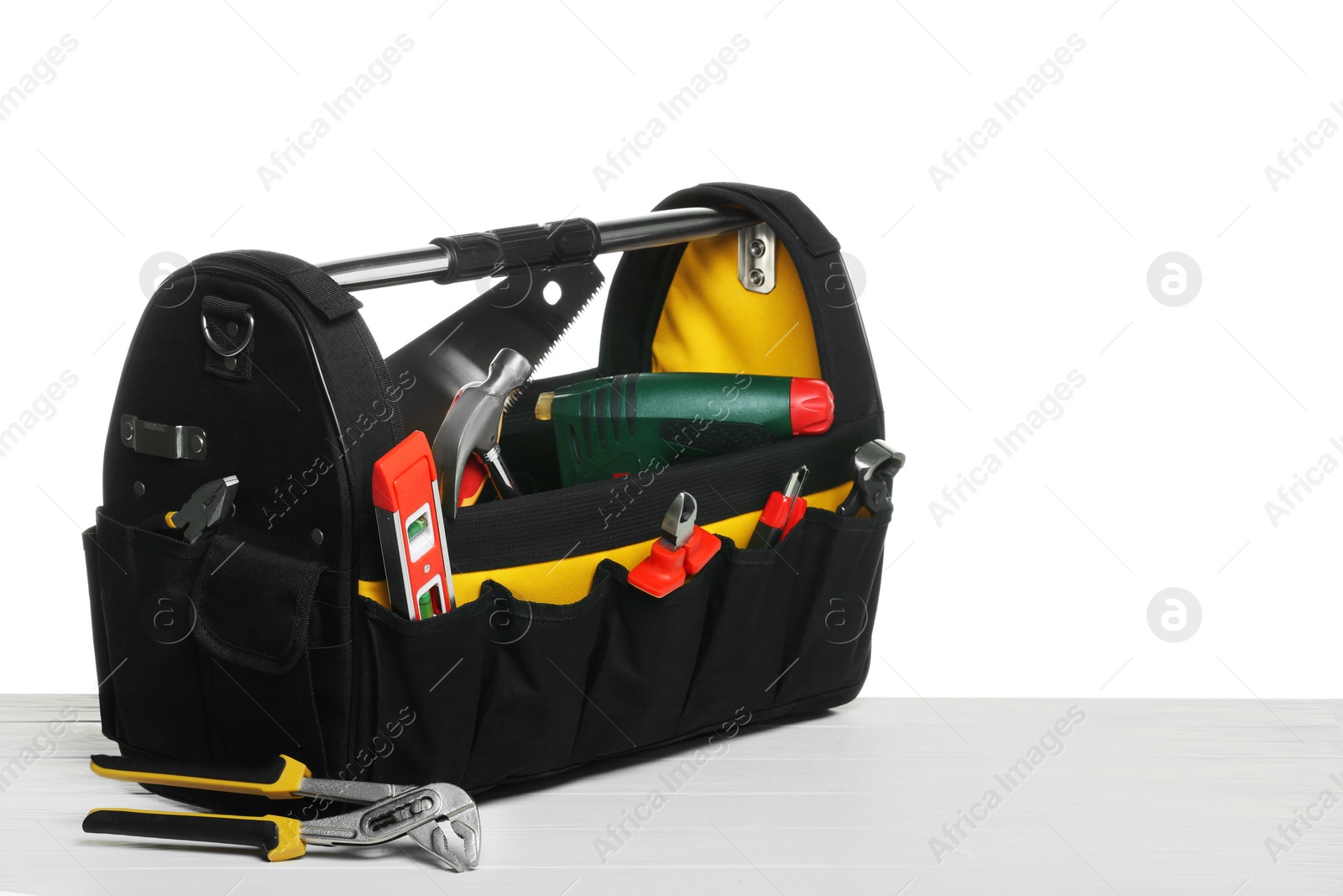 Photo of Bag with different tools on wooden table against white background