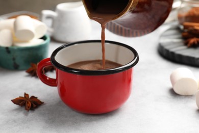 Photo of Pouring tasty hot chocolate into cup at light table, closeup