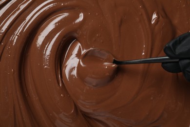 Person making tasty milk chocolate paste, top view