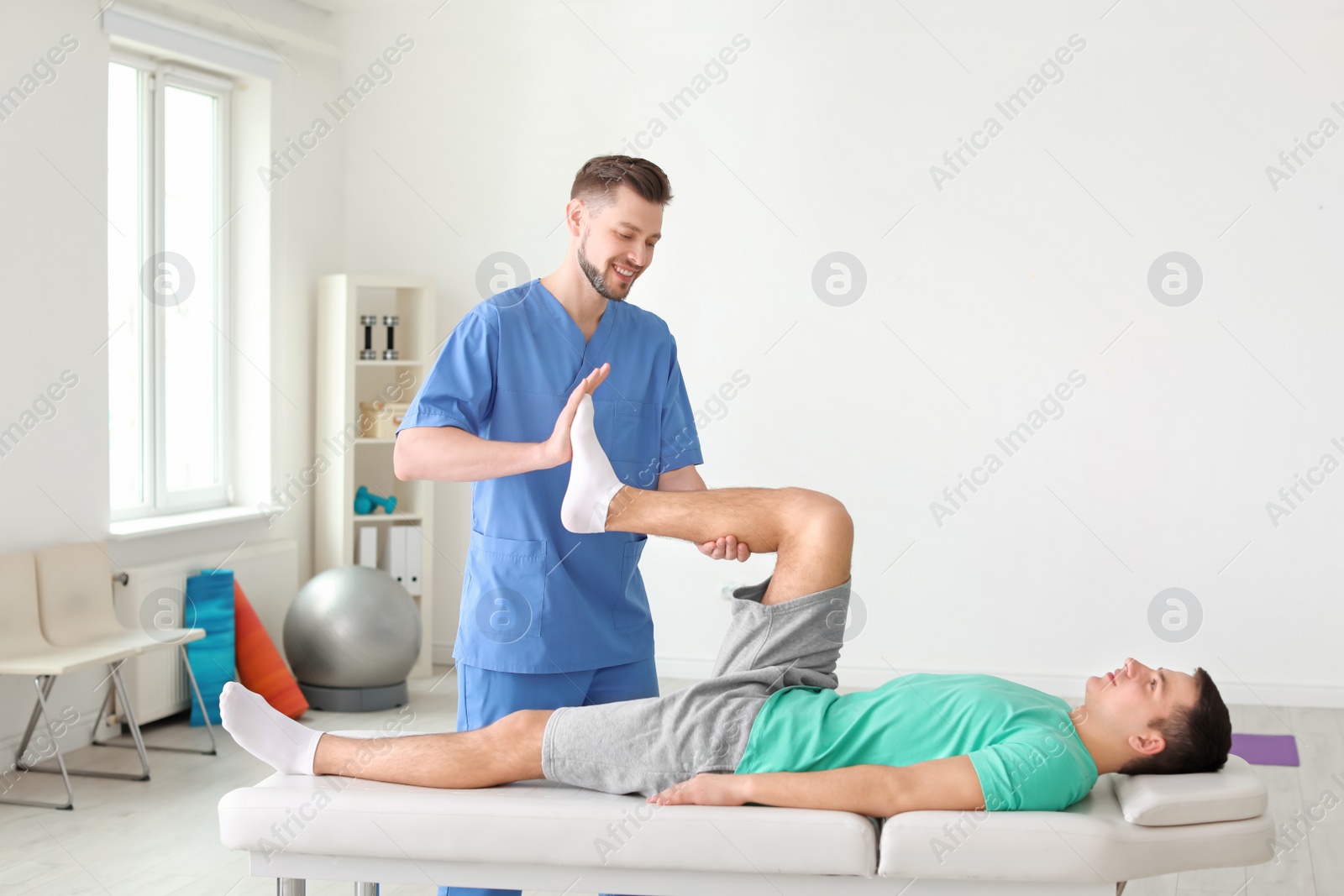 Photo of Physiotherapist working with male patient in clinic