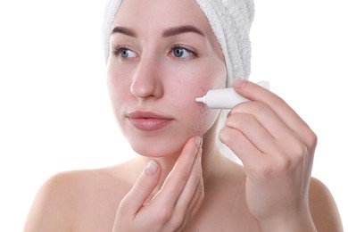 Young woman with acne problem applying cosmetic product onto her skin on white background