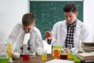 Teacher with pupil making experiment at table in chemistry class