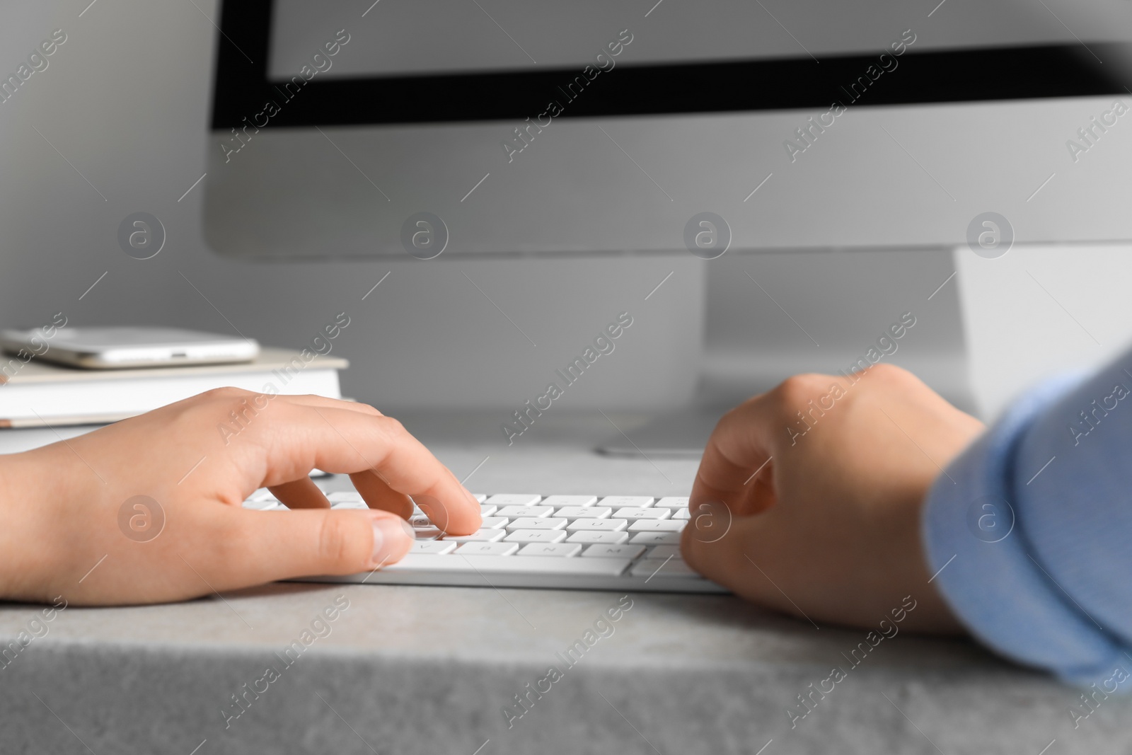 Photo of Woman working on modern computer at grey table, closeup