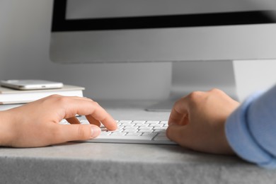 Photo of Woman working on modern computer at grey table, closeup