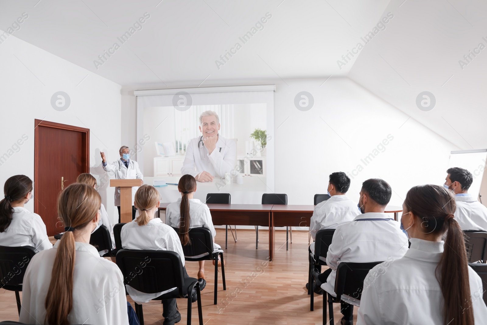 Image of Lecture with online participant. Doctors in meeting room. Using projector for videoconference