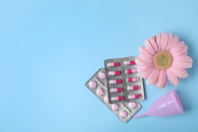 Photo of Flat lay composition with menstrual cup, pills and gerbera flower on color background, space for text. Gynecological care