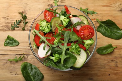 Photo of Tasty fresh vegetarian salad on wooden table, flat lay