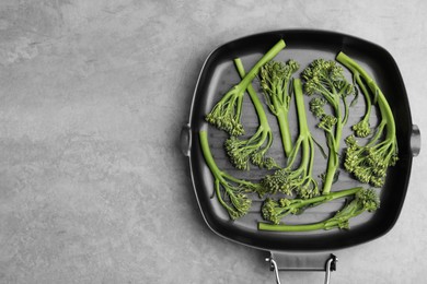 Photo of Pan with fresh raw broccolini on light grey table, top view and space for text. Healthy food