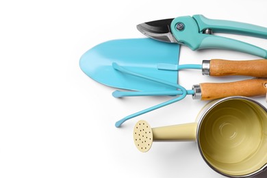 Watering can and gardening tools on white background, flat lay. Space for text