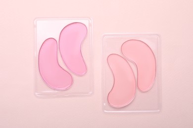 Photo of Packages with under eye patches on light pink background, flat lay. Cosmetic product