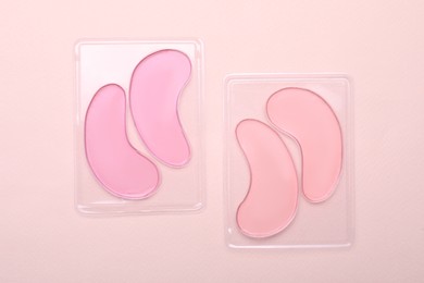 Packages with under eye patches on light pink background, flat lay. Cosmetic product