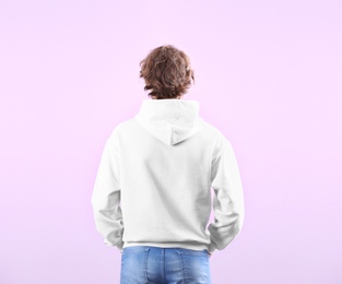 Man in hoodie sweater on color background. Space for design