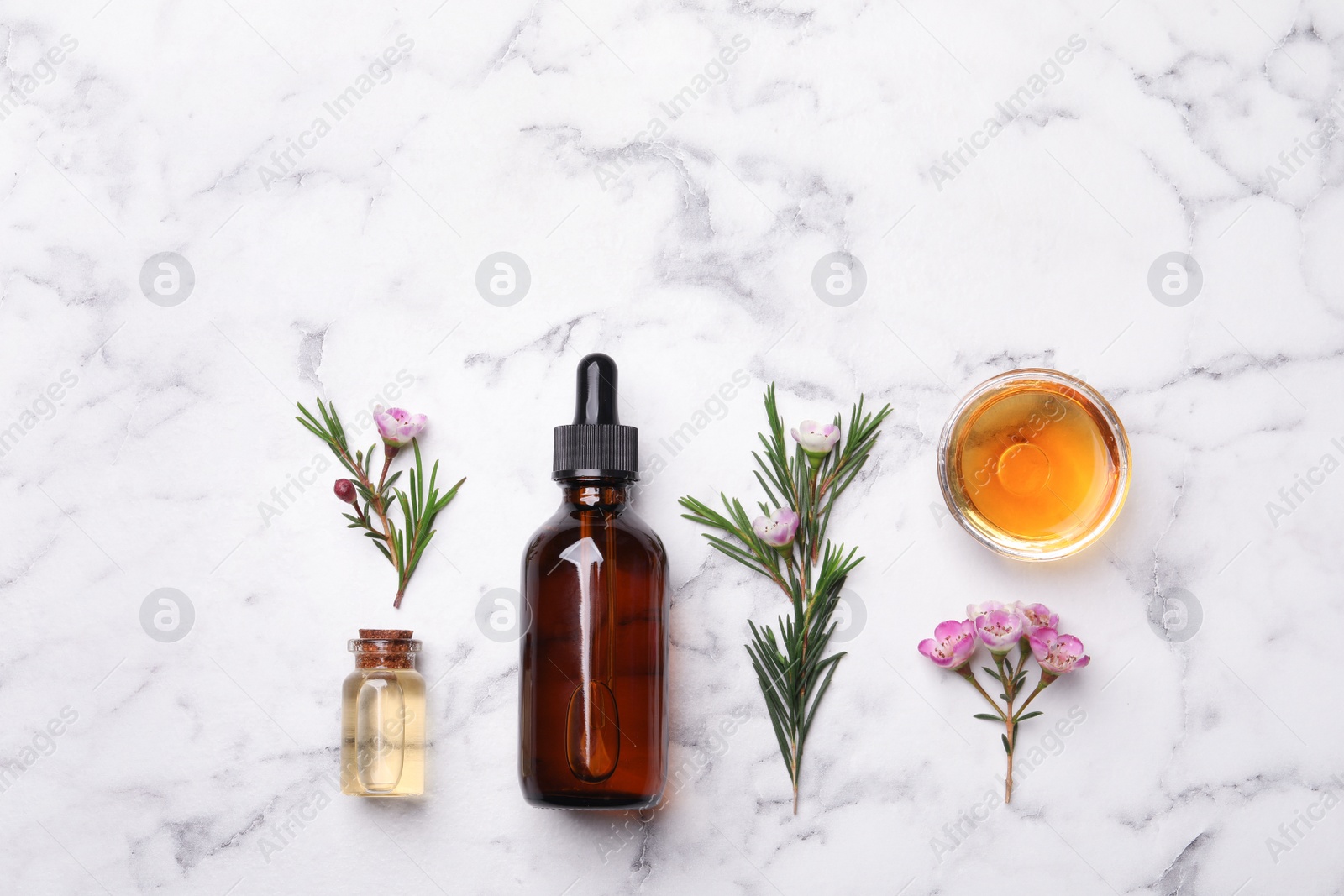 Photo of Flat lay composition with bottles of natural tea tree oil on marble table