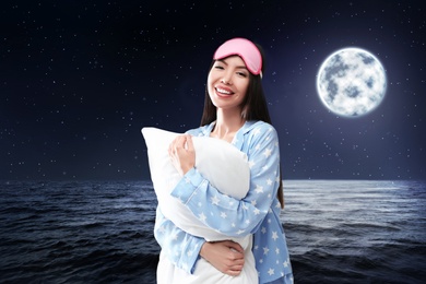 Image of Asian woman holding pillow, night starry sky with full moon on background. Bedtime