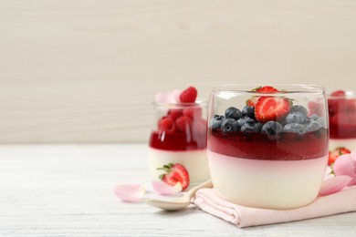 Photo of Delicious panna cotta with berries on white wooden table. Space for text