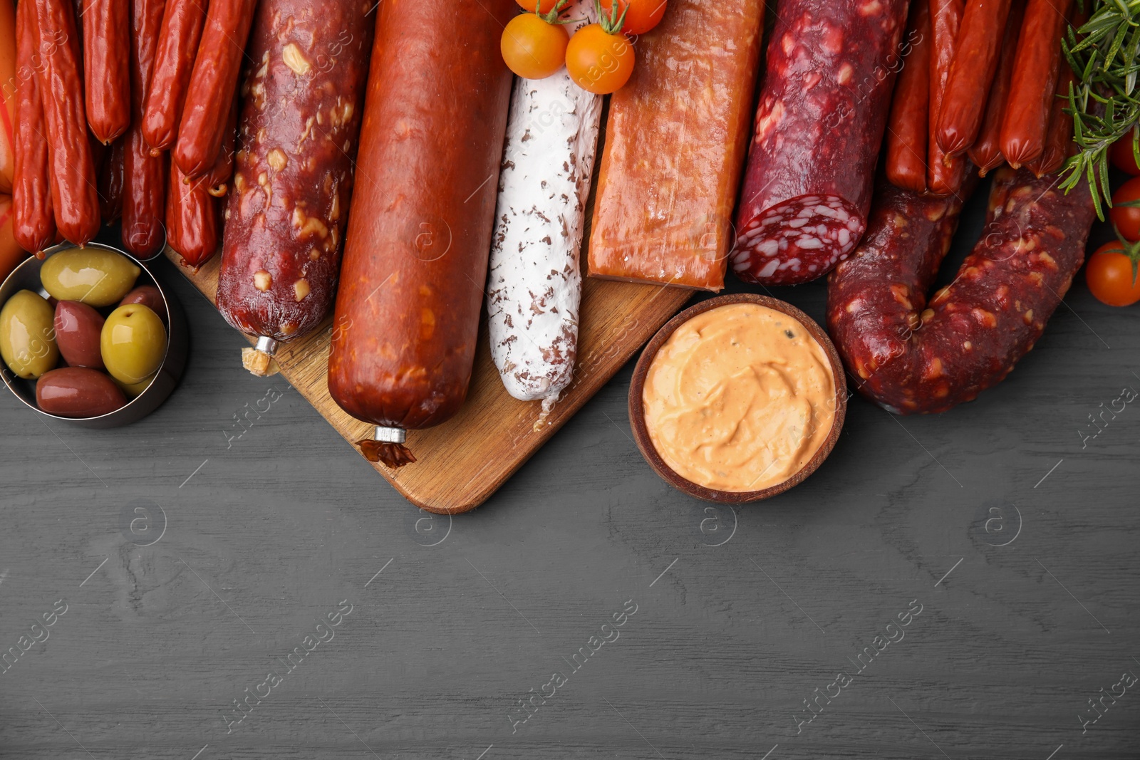 Photo of Different types of tasty sausages on grey wooden table, flat lay. Space for text