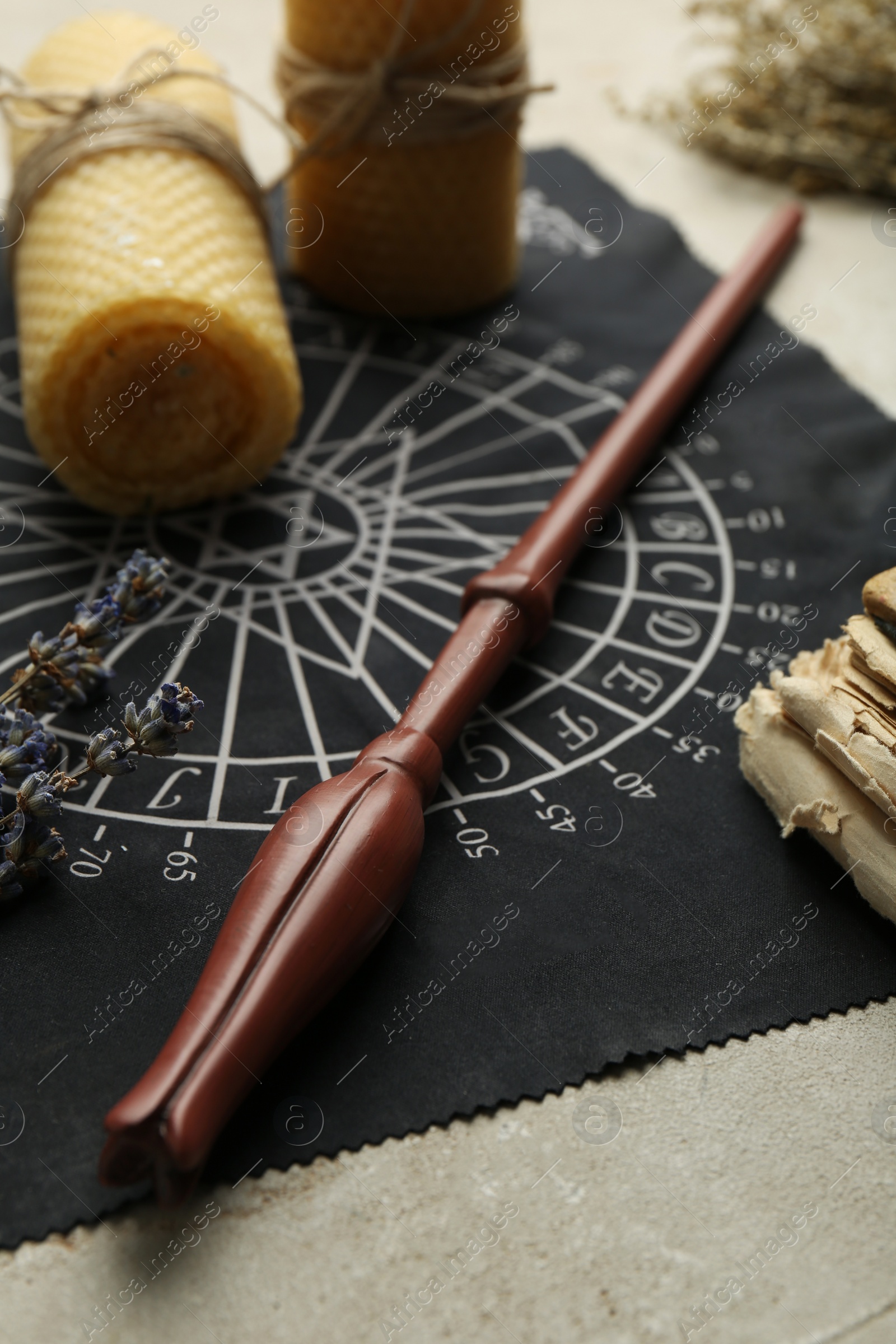 Photo of Magic wand, divination cloth and wax candles on light table, closeup