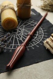 Photo of Magic wand, divination cloth and wax candles on light table, closeup
