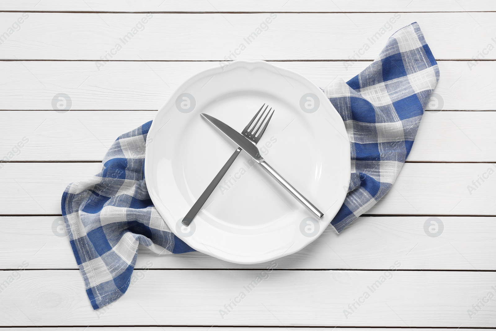 Photo of Clean plate with shiny silver cutlery on white wooden table, flat lay