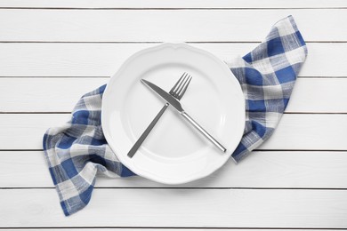 Photo of Clean plate with shiny silver cutlery on white wooden table, flat lay