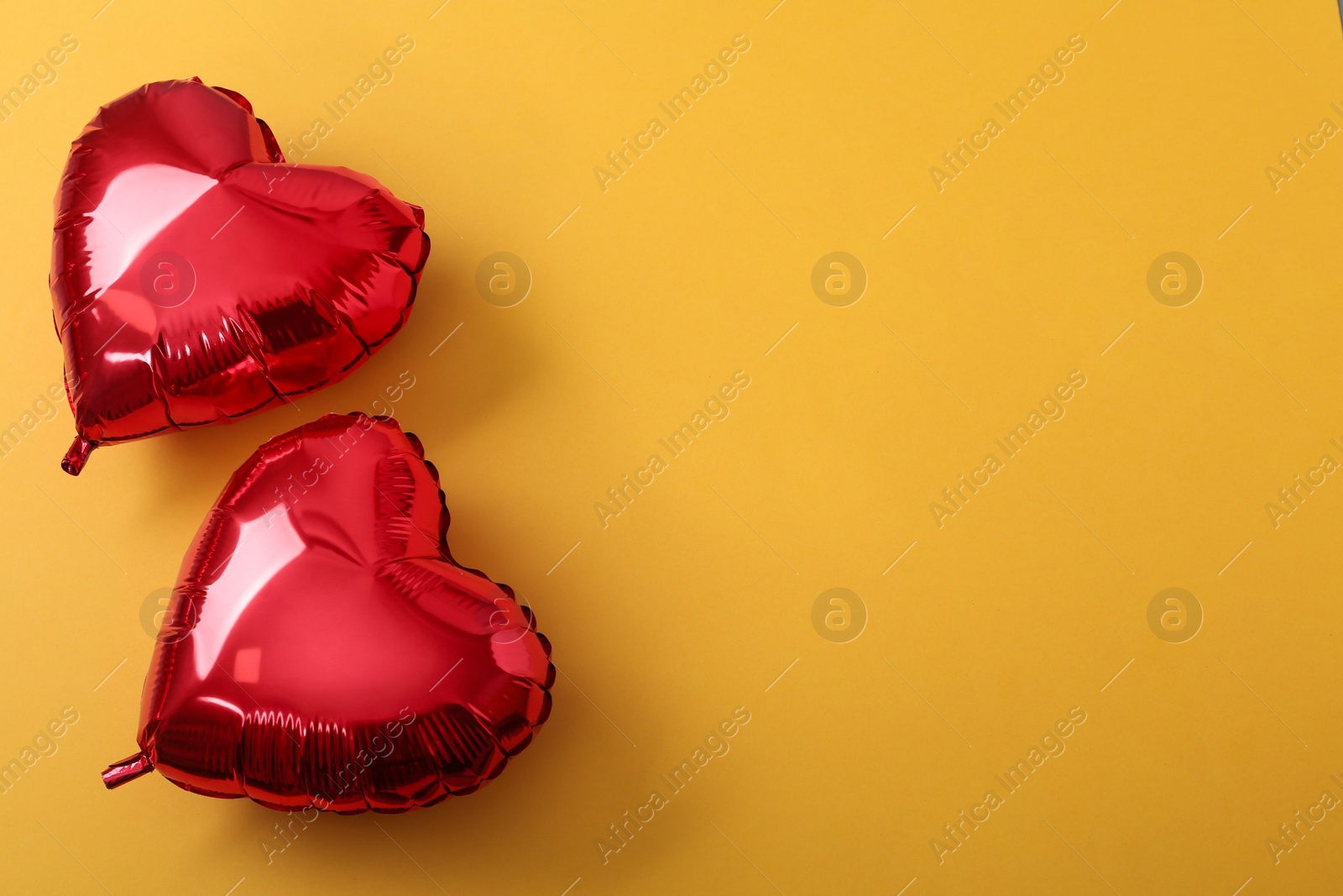 Photo of Red heart shaped balloons on yellow background, flat lay with space for text. Saint Valentine's day celebration