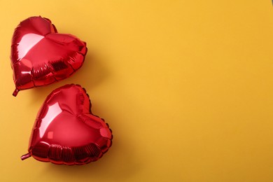 Photo of Red heart shaped balloons on yellow background, flat lay with space for text. Saint Valentine's day celebration