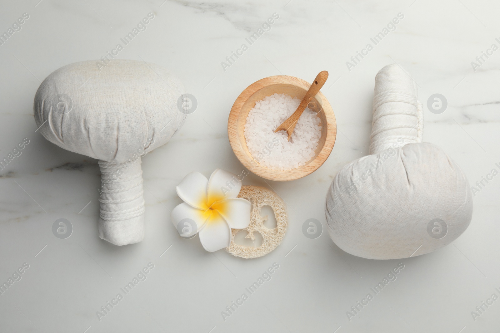 Photo of Flat lay composition with spa bags, sea salt and plumeria flower on white marble table