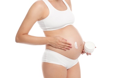 Photo of Pregnant woman applying body cream on belly against white background, closeup