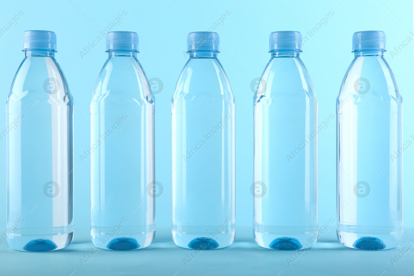 Photo of Collection of plastic bottles with water on color background