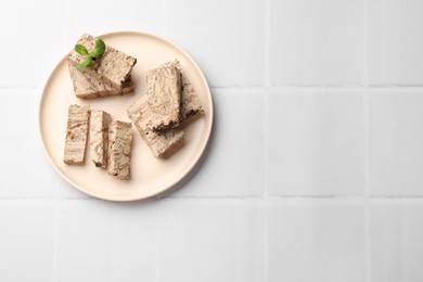 Photo of Tasty chocolate halva with mint on white tiled table, top view