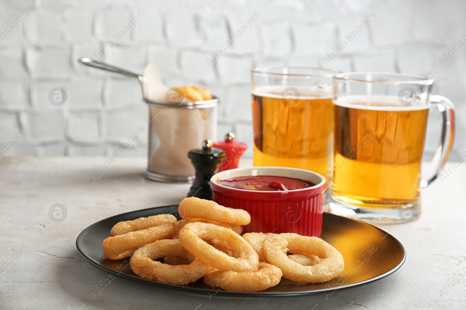 Photo of Plate with onion rings and bowl of sauce on table