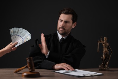 Photo of Woman giving bribe to judge at wooden table against black background