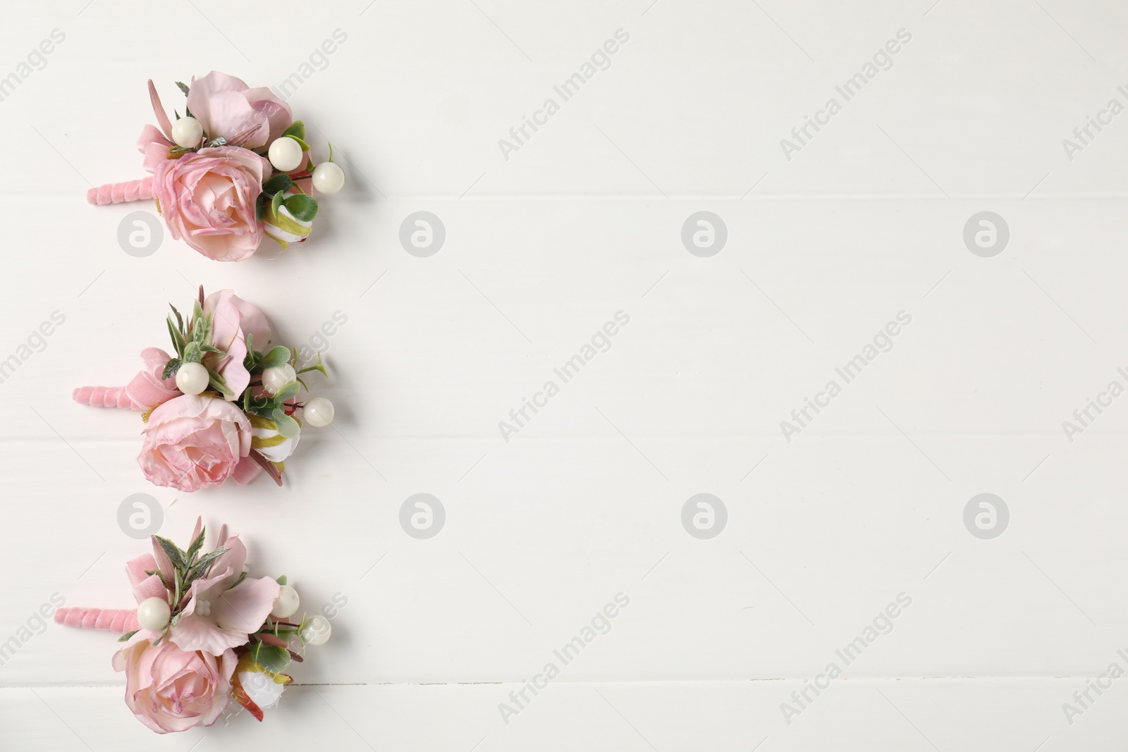 Photo of Beautiful boutonnieres on white background, flat lay. Space for text