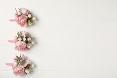 Beautiful boutonnieres on white background, flat lay. Space for text